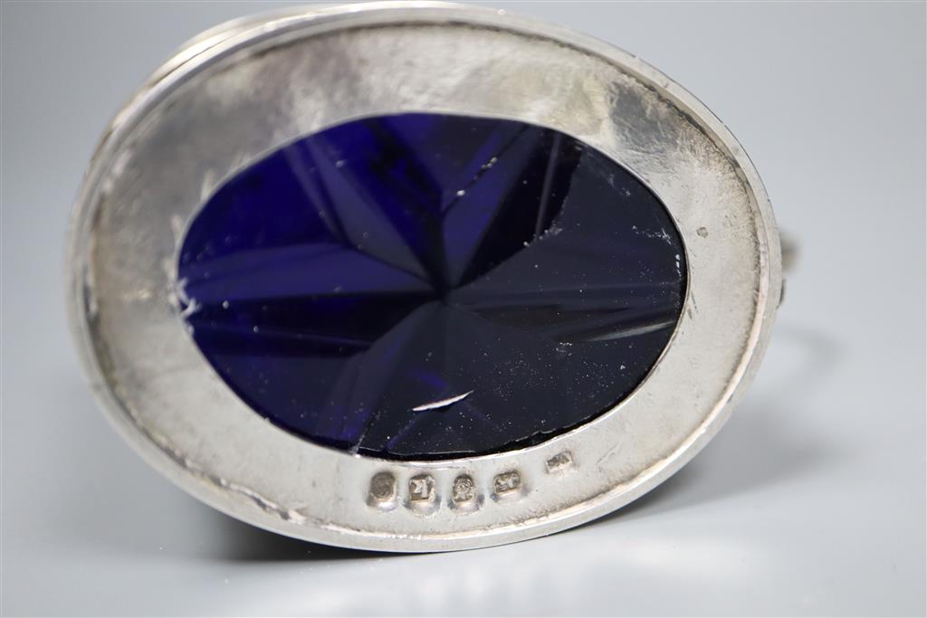 A George III pierced silver oval mustard pot, maker, W?, London, 1785, with blue glass liner and associated plated spoon.
